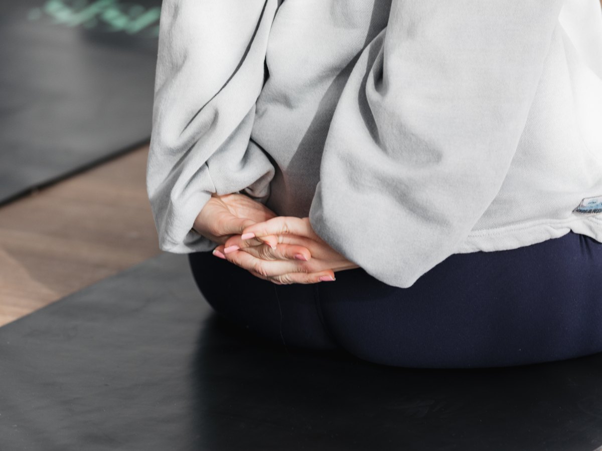 Sitting cross-legged in stillness on a mat in the SiSU mat studio